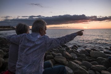 Senior couple woman and man, family, looking at the sunset on the ocean coastline together with a love hug. Feeling positive vibes in their third age.