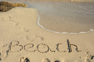The word beach written in the sand on a beach
