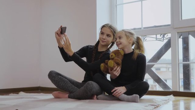 Two little girls makes selfie with teddy bear