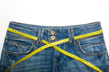 Jeans and the measure tape on a white background