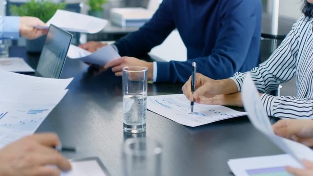 Moving Camera Flyover Shot of the Business Meeting Room Table with People Sharing Documents with Pie Charts and Statistics, Tablet and Laptop Screens. Shot on RED EPIC-W 8K Helium Cinema Camera.