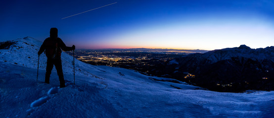 Obraz premium Hiker looking at a winter mountain landscape while the ISS (International Space Station) leaves his trail in the evening sky.