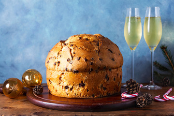 Italian festive bread panetton on a table decorated for Christmas. and two glasses of champagne. New Year's traditional dessert
