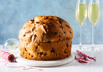Italian festive bread panetton on a table decorated for Christmas. and two glasses of champagne. New Year's traditional dessert