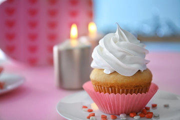 Plate with delicious cupcake on table