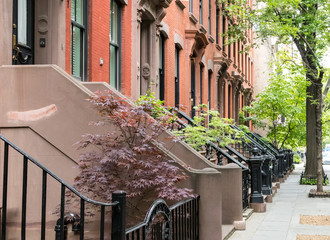 Quiet neighborhood street sidewalk lined with historic brownstone buildings in a Greenwich Village...