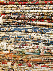 Vertical stack of colorful Middle Eastern style rugs and carpets fabric background pattern texture