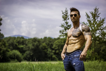 Handsome Muscular Shirtless Hunk Man Outdoor in City Park Standing on Grass. Showing Healthy Muscle Body While Looking away