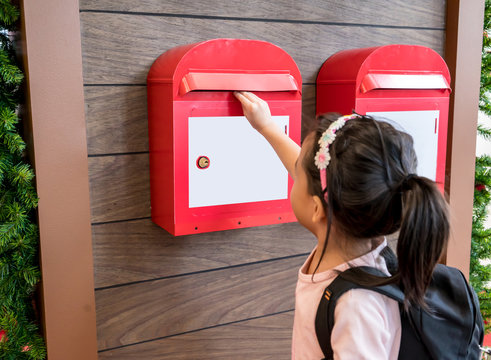 Asian Kid Sending Her Mail In The Red Metal Mailbox