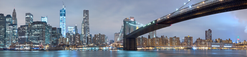 Brooklyn bridge and Manhattan glowing at night, New York City. Scenic panorama.