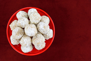 Stacked Russian tea cake holiday cookies on a bright red ceramic plate on a red background

