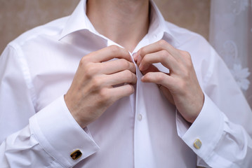 The man dressed and buttoning a white shirt