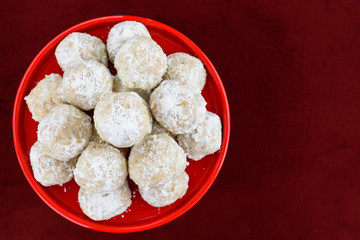 Stacked Russian tea cake holiday cookies on a bright red ceramic plate on a red background
