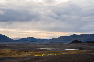 A bare landscape with background mountains and clouds in Iceland. 
