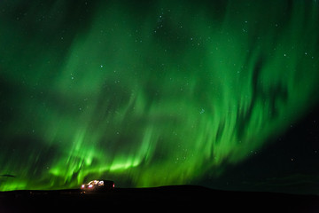 Green northern lights in Iceland with a camper van on the ground. 