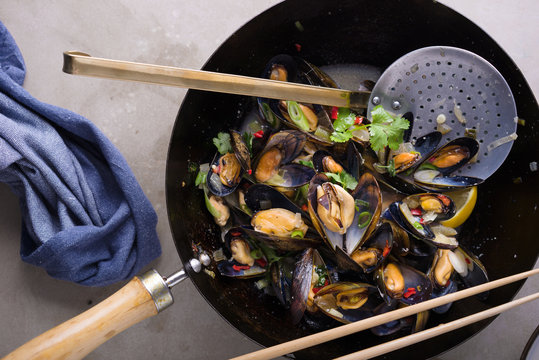 Asian style steamed mussels in a wok.