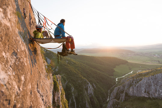 two climbers watching the sunset from their portaledge - Powered by Adobe