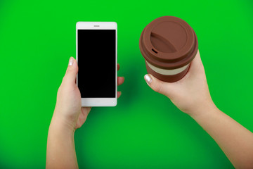 Obraz na płótnie Canvas Female hands hold smartphone and cup of coffe