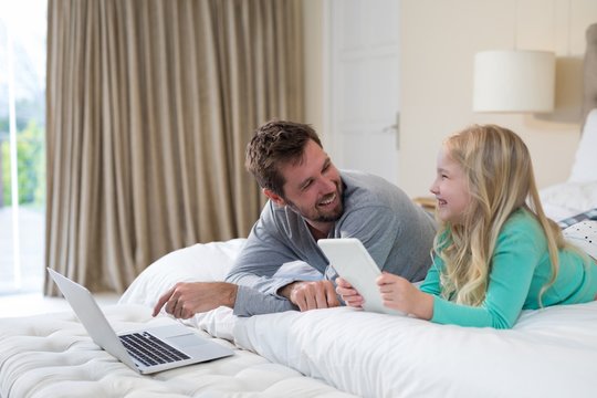 Father and daughter using laptop and digital tablet