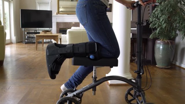 Woman using a knee scooter in a house