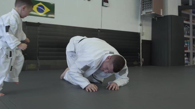 Instructor practicing Jiu-jitsu moves with a boy