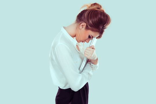 Stressed At Work. Unhappy Upset Sad Young Woman In Side Profile Bending Head On Laptop Screen Isolated Light Blue Background. Image Toned With Blue Filter.