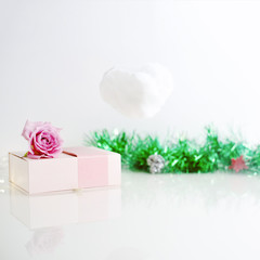 Pink present box with rose on it and cloud with christmas tree decoration on the background. New year minimal concept.
