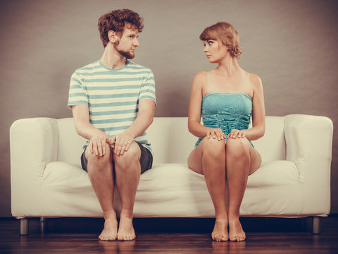 woman and man sitting on sofa looking to each other.