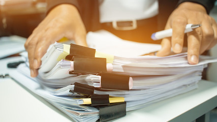 Businesswoman hands working on Stacks of documents files for finance in office. Business report papers or Piles of unfinished document achieves with black clip paper. Concept of Business Annual Report - obrazy, fototapety, plakaty
