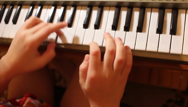 a child plays the keyboard of a musical instrument, music lessons