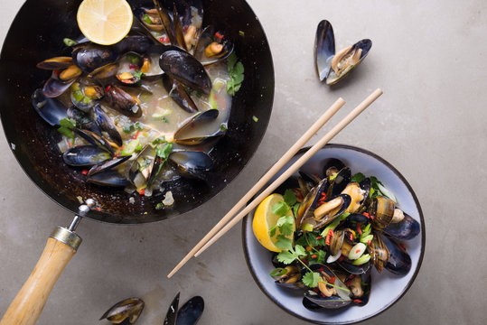 Cooked mussels in a bowl and wok.