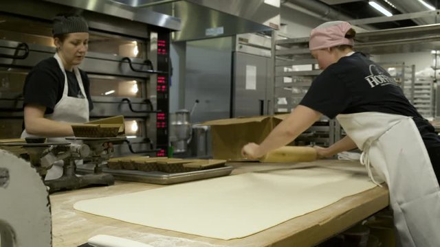 Baker stretching dough with a rolling pin