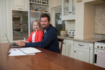 Father and daughter working on laptop at home