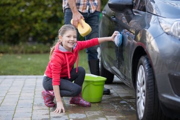 Naklejka premium Teenage girl washing a car on a sunny day