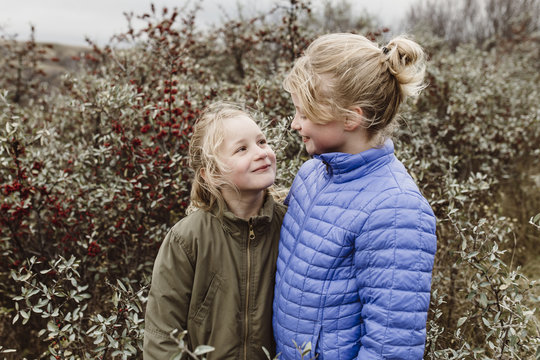 Outdoor portrait of young sisters in field of berries