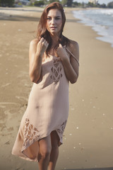 Fototapeta na wymiar Young female model in the dress on the beach