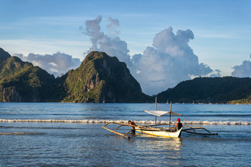 Two man with bangka boat with beautiful sunset in El Nido, Palawan island, Philippines