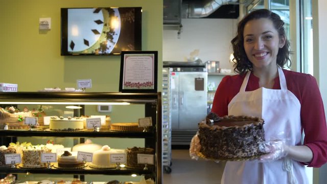 Baker presenting a cake to camera