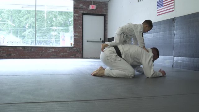 Instructor practicing Jiu-jitsu moves with a boy