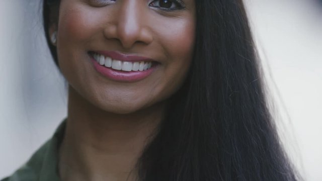 Attractive portrait of a young asian woman smiling to camera, in slow motion