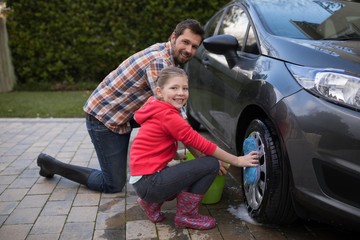 Teenage girl and father washing a car