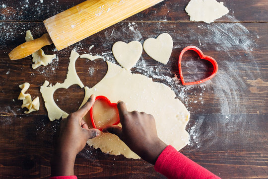 Black girl's hand cutting heart shaped cookies