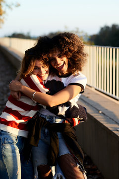 Smiling girlfriends hugging at sunset.