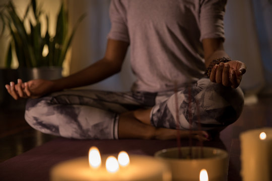 Woman meditating in candle-lit apartment