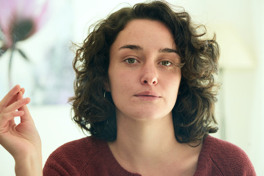 Attractive woman with curly hair smoking cigarette.