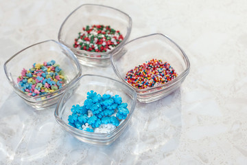 Marble background. Four transparent glass cups with decorations for confectionery and baking.