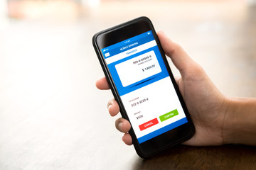 Hand holding smartphone showing online electronic internet banking application on screen