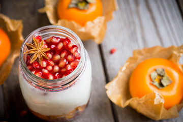 Healthy breakfast with yogurt, persimmon and pomergranate seeds. Selective focus. Shallow depth of field.