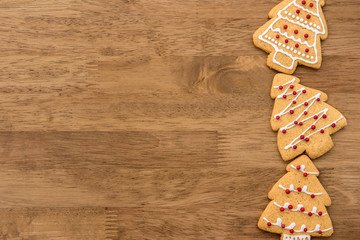 Christmas tree shape gingerbread cookies at border of wood background