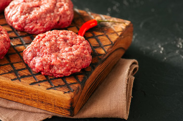 Close up of raw ground meat beef burgers on a wooden board.